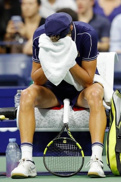 Holger Vitus Nodskov Rune of Denmark puts his face into the towel during a break against Novak Djokovic of Serbia during his Men's Singles first...
