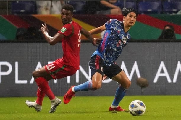 Genki Haraguchi of Japan and Amjad Al Harthi of Oman compete for the ball during FIFA World Cup Asian Qualifier Final Round Group B match between...