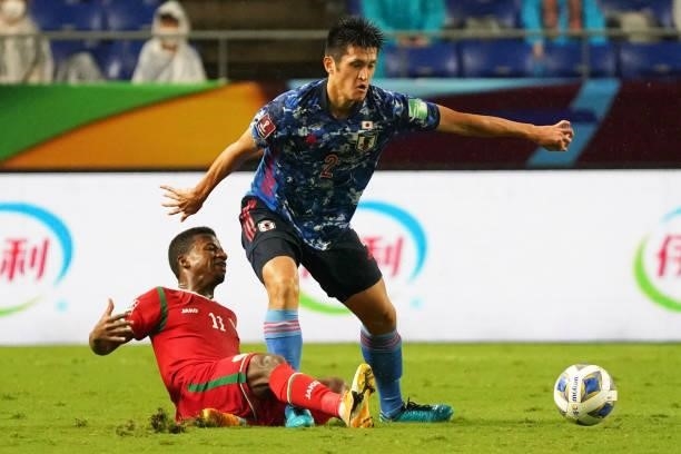 Naomichi Ueda of Japan and Almandhar Al Alawi of Oman compete for the ball during FIFA World Cup Asian Qualifier Final Round Group B match between...