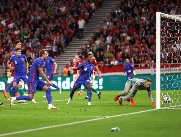 Harry Kane and Raheem Sterling of England watch as Peter Gulacsi of Hungary fails to save a shot from Harry Maguire of England during the 2022 FIFA...