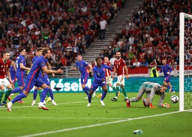 Harry Kane and Raheem Sterling of England watch as Peter Gulacsi of Hungary fails to save a shot from Harry Maguire of England during the 2022 FIFA...