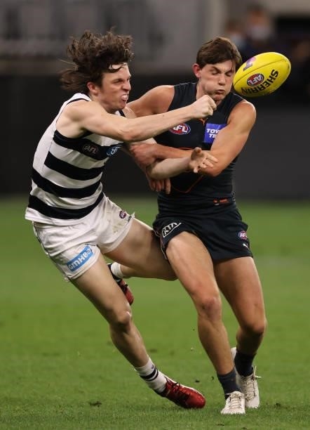 Max Holmes of the Cats handballs whilst being tackled by Conor Stone of the Giants during the AFL First Elimination Final match between Geelong Cats...