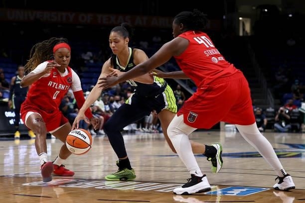 Forward Isabelle Harrison of the Dallas Wings dribbles the ball against guard Odyssey Sims of the Atlanta Dream and forward Shekinna Stricklen of the...
