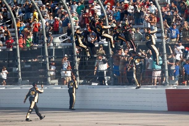 Noah Gragson, driver of the Bass Pro Shops/TrueTimber/BRCC Chevrolet, and crew members climb the fence to celebrate with fans after winning the...
