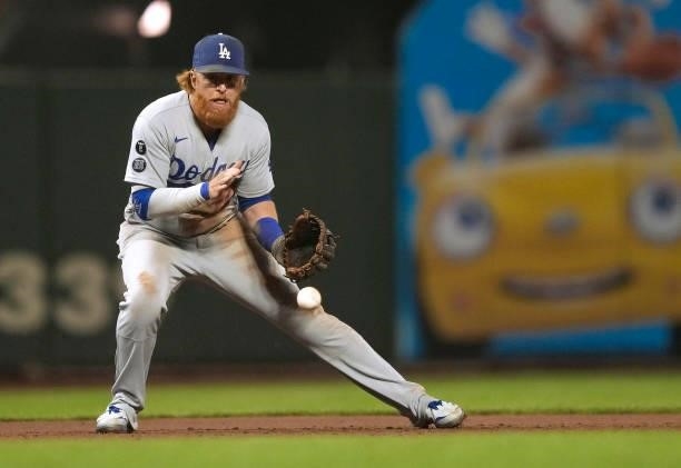 Justin Turner of the Los Angeles Dodgers watches the ball kick off his glove for a base hit off the bat of Kris Bryant of the San Francisco Giants in...