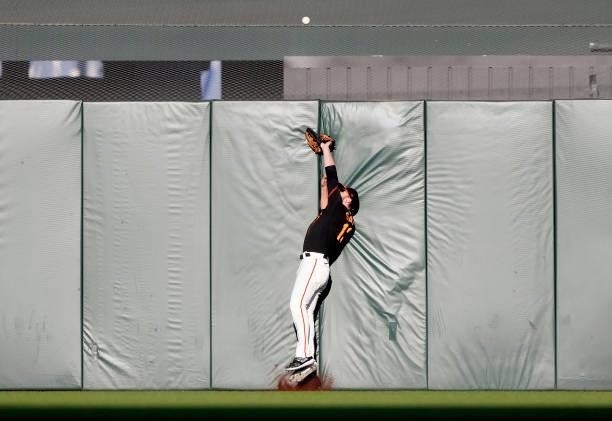 Austin Slater of the San Francisco Giants collides with the wall and watches the ball go over for a lead off solo home run from Trea Turner of the...