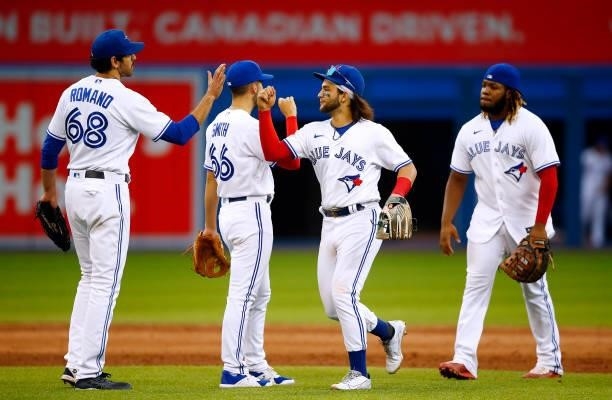 Jordan Romano, Kevin Smith, Bo Bichette and Vladimir Guerrero Jr. #27 of the Toronto Blue Jays celebrate the win following a MLB game against the...