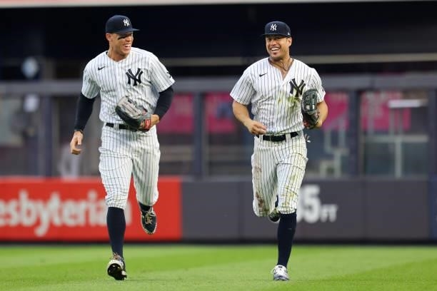Right fielder Giancarlo Stanton of the New York Yankees laughs with Aaron Judge after he made a diving catch on a ball hit by Anthony Santander of...