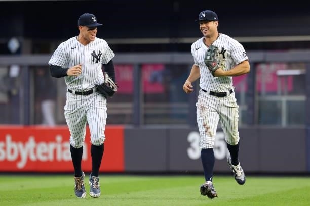 Right fielder Giancarlo Stanton of the New York Yankees laughs with Aaron Judge after he made a diving catch on a ball hit by Anthony Santander of...