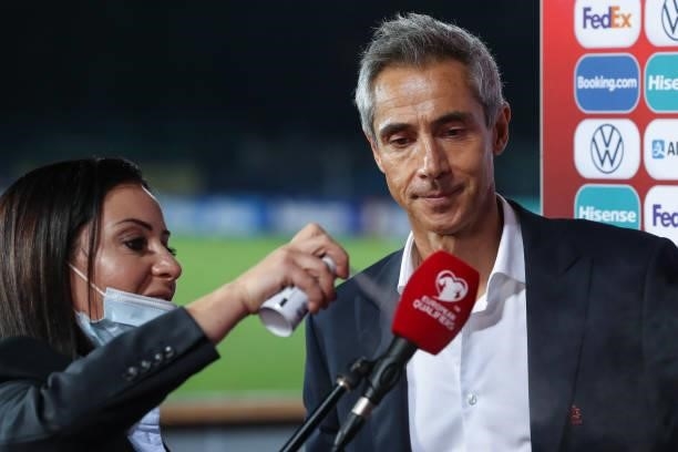 Member of staff sanitizes a microphone beofre Paulo Sousa Head coach of Poland is interviewed following the final whistle of the 2022 FIFA World Cup...