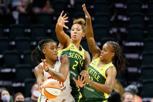 Shavonte Zellous of the Washington Mystics looks to pass while pressured by Mercedes Russell and Epiphanny Prince of the Seattle Storm during the...