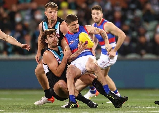 Tom Liberatore of the Bulldogs handballs whilst being tackled by Scott Lycett of the Power during the AFL Second Preliminary Final match between Port...