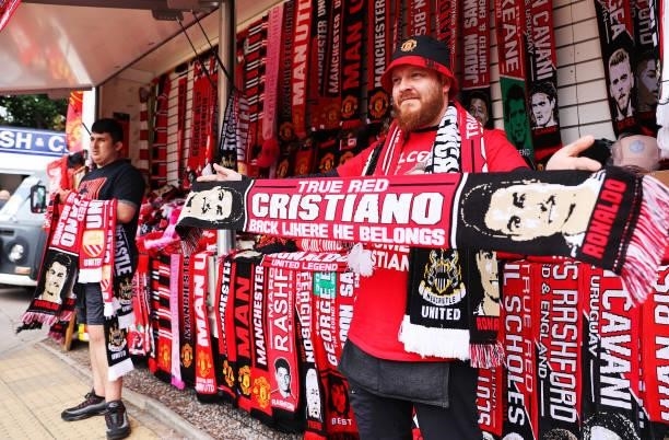 Merchandise seller holds a scarf with the face of Cristiano Ronaldo of Manchester United on outside the stadium prior to the Premier League match...