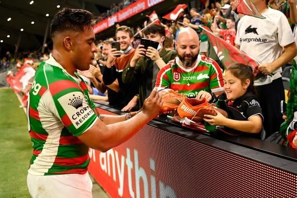 Tevita Tatola of the Rabbitohs signs and gives his boots to a young supporter in the crowd as he celebrates victory during the NRL Qualifying Final...