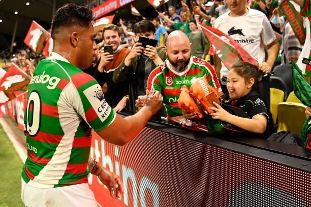 Tevita Tatola of the Rabbitohs signs and gives his boots to a young supporter in the crowd as he celebrates victory during the NRL Qualifying Final...
