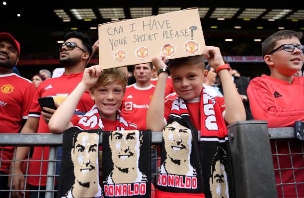 Fans of Manchester United hold aloft a sign asking for the shirt of Cristiano Ronaldo of Manchester United prior to the Premier League match between...