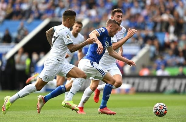 Jamie Vardy of Leicester City runs with the ball whilst under pressure from Joao Cancelo and Aymeric Laporte of Manchester City during the Premier...