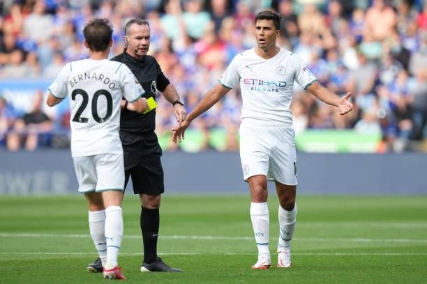 Rodrigo of Manchester City interacts with Match Referee, Paul Tierney during the Premier League match between Leicester City and Manchester City at...