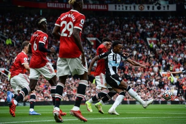 Joe Willock of Newcastle United passes the ball as he is surrounded by Manchester United players during the Premier League match between Manchester...