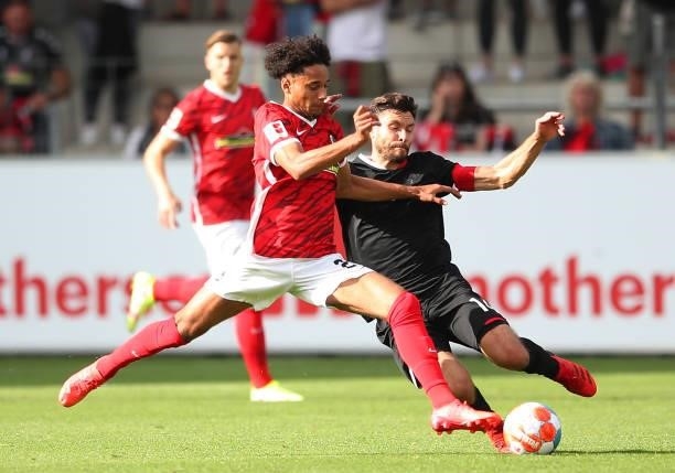 Jonas Hector of 1.FC Koeln is challenged by Kevin Schade of SC Freiburg during the Bundesliga match between Sport-Club Freiburg and 1. FC Köln at...