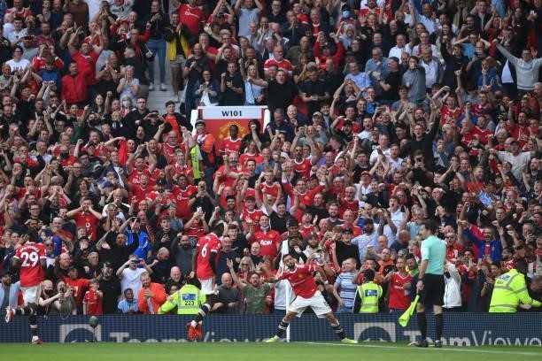 Bruno Fernandes of Manchester United celebrates after scoring their side's third goal as fans celebrate during the Premier League match between...