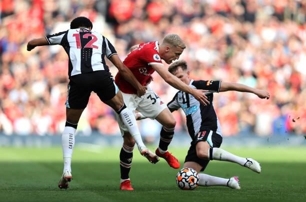 Donny van de Beek of Manchester United is challenged by Jamal Lewis and Matt Ritchie of Newcastle United during the Premier League match between...