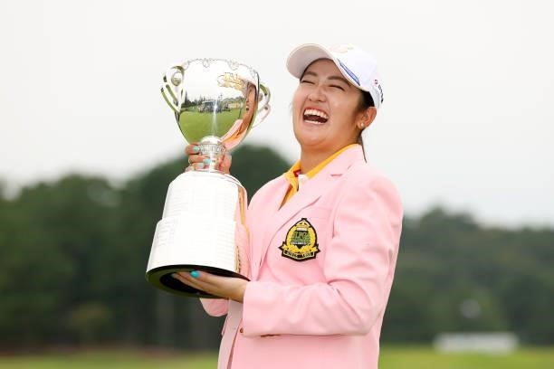 Mone Inami of Japan laughs as she poses with the trophy after winning the tournament following the final round of the JLPGA Championship Konica...