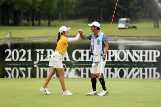 Mone Inami of Japan fist bumps with her caddie after winning the tournament on the 18th green during the final round of the JLPGA Championship Konica...