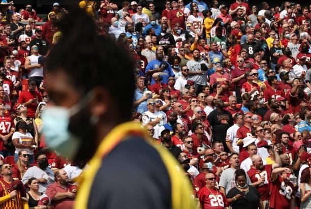 Fans look on as a security guard on the field wears a mask during the game between the Washington Football Team and the Los Angeles Chargers at...
