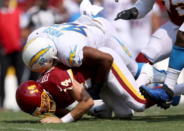 Ryan Fitzpatrick of the Washington Football Team is tackled by Uchenna Nwosu of the Los Angeles Chargers during the second quarter at FedExField on...