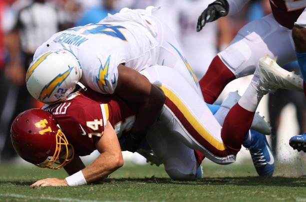 Ryan Fitzpatrick of the Washington Football Team is hit by Uchenna Nwosu of the Los Angeles Chargers during the first half at FedExField on September...