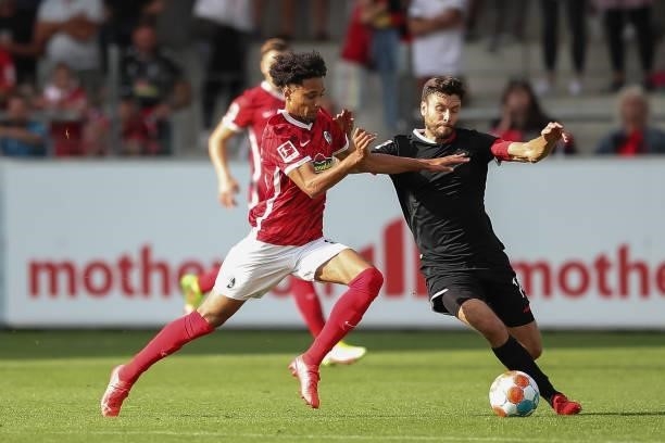 Jonas Hector of 1.FC Koeln is tackled by Kevin Schade of SC Freiburg during the Bundesliga match between Sport-Club Freiburg and 1. FC Köln at...