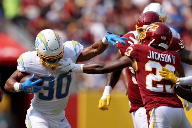 Austin Ekeler of the Los Angeles Chargers breaks a tackle from William Jackson of the Washington Football Team at FedExField on September 12, 2021 in...
