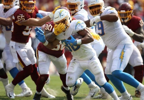 Austin Ekeler of the Los Angeles Chargers is tackled by Montez Sweat of the Washington Football Team during the third quarter at FedExField on...