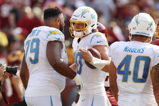Justin Herbert of the Los Angeles Chargers laughs with Trey Pipkins against the Washington Football Team at FedExField on September 12, 2021 in...