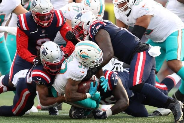 Myles Gaskin of the Miami Dolphins is tackled by several members of the New England Patriots during the first quarter at Gillette Stadium on...