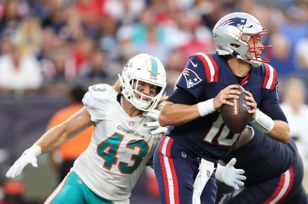 Mac Jones of the New England Patriots is pursued by Andrew Van Ginkel of the Miami Dolphins during the game at Gillette Stadium on September 12, 2021...