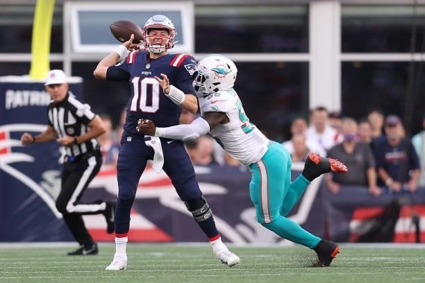 Mac Jones of the New England Patriots throws a pass under pressure from Jerome Baker of the Miami Dolphins at Gillette Stadium on September 12, 2021...