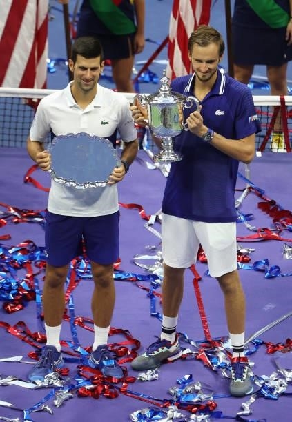Novak Djokovic of Serbia holds the runner-up trophy alongside Daniil Medvedev of Russia who celebrates with the championship trophy after winning...