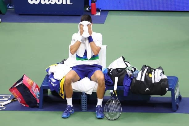 Novak Djokovic of Serbia covers his face during a changeover in the third set as he plays against Daniil Medvedev of Russia in the third set of the...