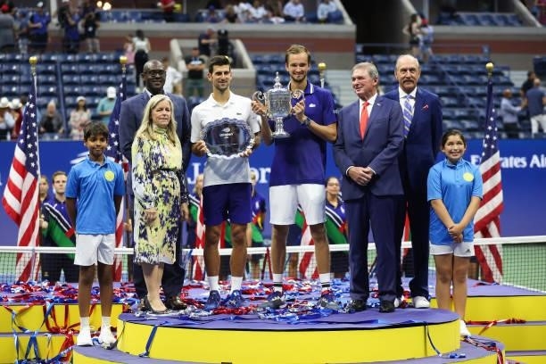Novak Djokovic of Serbia holds the runner-up trophy alongside Daniil Medvedev of Russia who celebrates with the championship trophy after winning...
