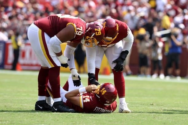 Offensive tackle Ereck Flowers and offensive tackle Charles Leno Jr. #72 try and help up quarterback Ryan Fitzpatrick of the Washington Football Team...