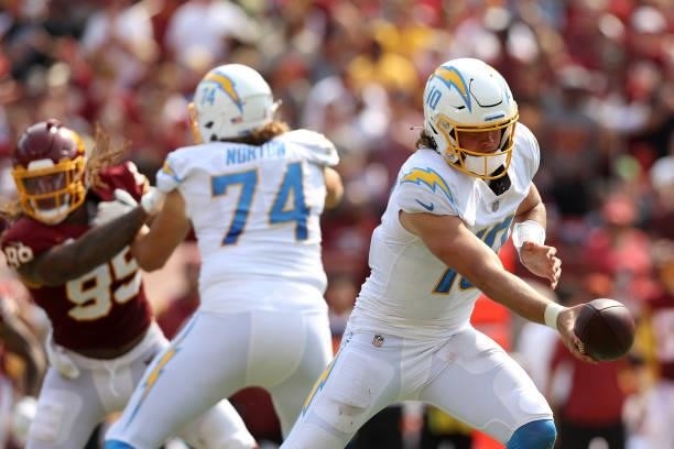 Quarterback Justin Herbert of the Los Angeles Chargers hands the ball off against the Washington Football Team at FedExField on September 12, 2021 in...
