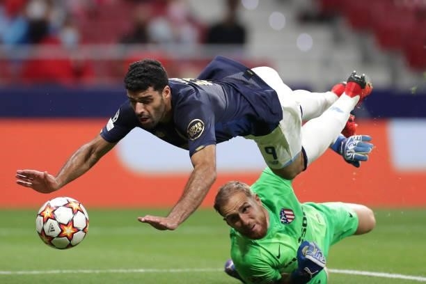 Mehdi Taremi of FC Porto is tackled by Jan Oblak of Atletico Madrid during the UEFA Champions League group B match between Atletico Madrid and FC...