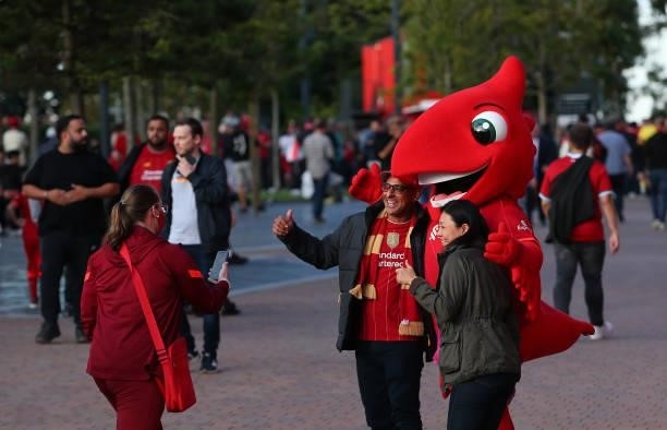 Supporters of Liverpool pose for photographs with Mighty Red the Liverpool mascot prior to the UEFA Champions League group B match between Liverpool...