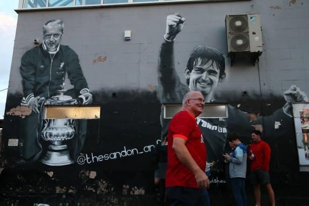 Supporter of Liverpool passes a mural of Bill Shankly and Kenny Dalglish outside Anfield prior to the UEFA Champions League group B match between...