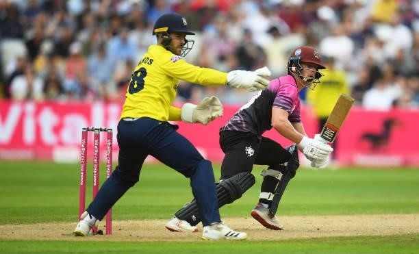 Tom Abell of Somerset plays a shot as Lewis McManus of Hampshire Hawks looks on during the Semi-Final of the Vitality T20 Blast match between...