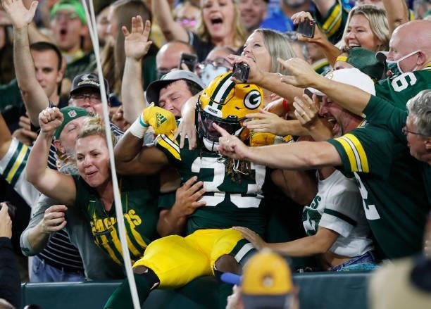 Aaron Jones of the Green Bay Packers does the Lambeau Leap to celebrate a touchdown with fans against the Detroit Lions during the first half at...