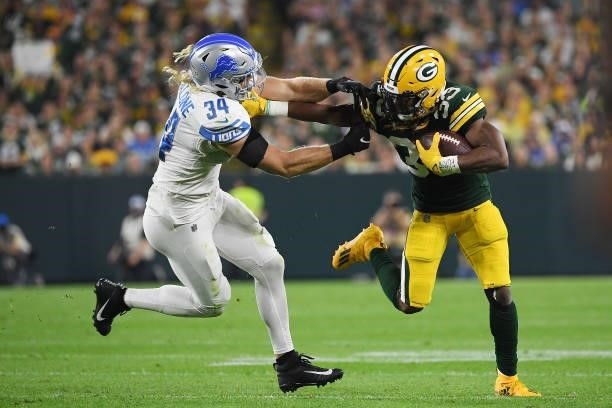 Aaron Jones of the Green Bay Packers shakes free from the hands of Alex Anzalone of the Detroit Lions during the first half at Lambeau Field on...