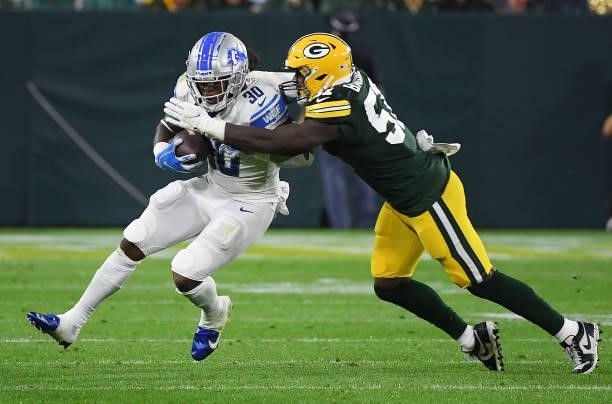 Jamaal Williams of the Detroit Lions is tackled by Krys Barnes of the Green Bay Packers during the second half at Lambeau Field on September 20, 2021...
